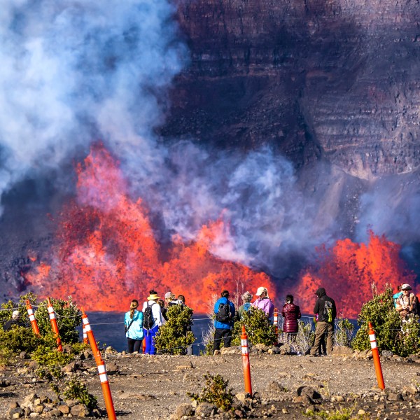 In this photo provided by the National Park Service, people watch as an eruption takes place on the summit of the Kilauea volcano in Hawaii, Monday, Dec. 23, 2024. (Janice Wei/NPS via AP)