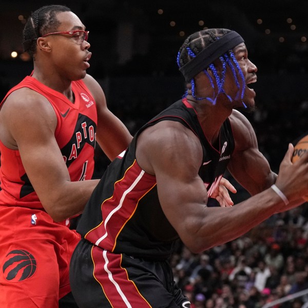 Miami Heat's Jimmy Butler, right, drives to the net against Toronto Raptors' Scottie Barnes, front left, during second-half NBA basketball game action in Toronto, Sunday, Dec. 1, 2024. (Chris Young/The Canadian Press via AP)