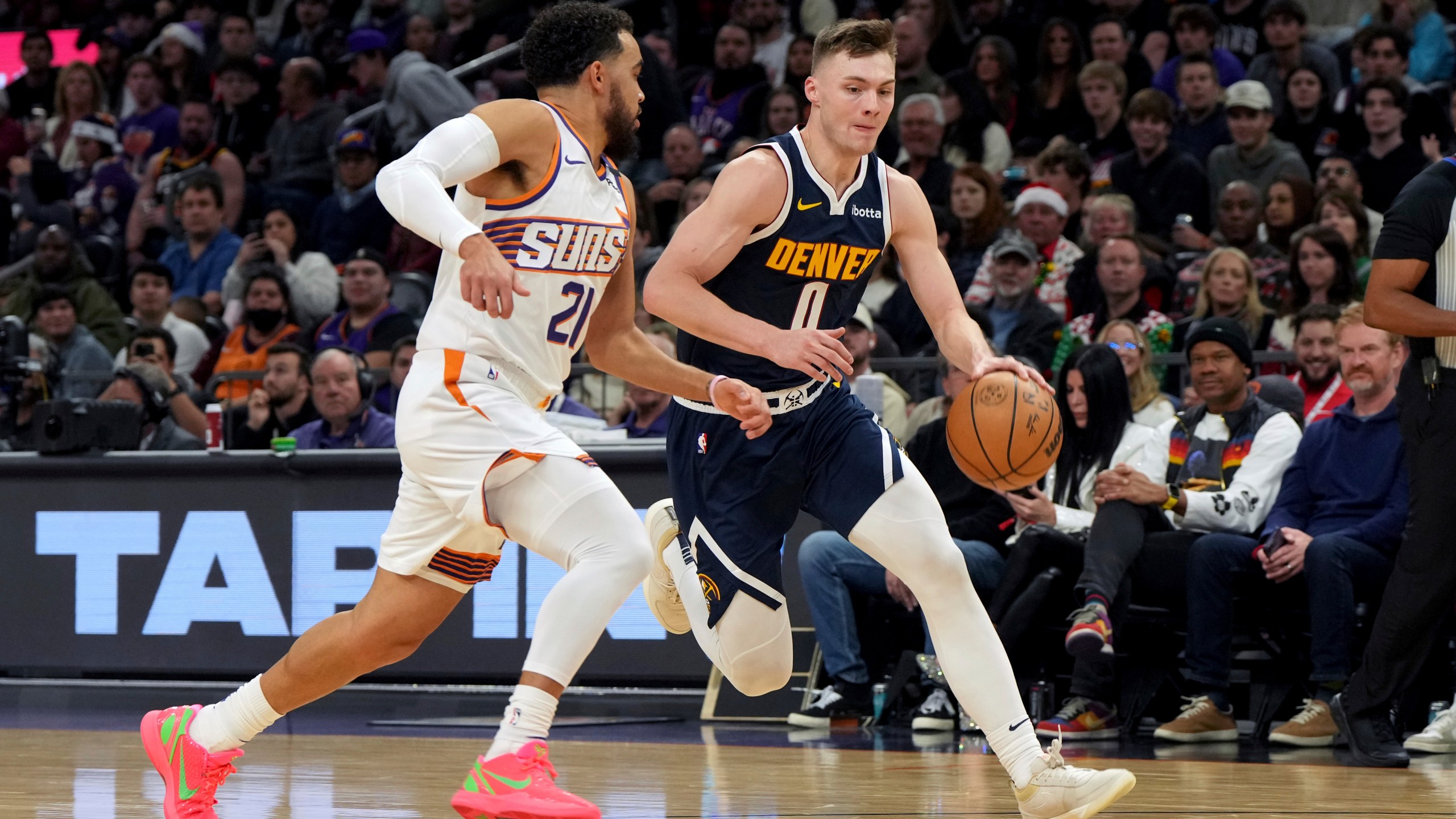 Denver Nuggets guard Christian Braun drives on Phoenix Suns guard Tyus Jones during the first half of an NBA basketball game, Wednesday, Dec. 25, 2024, in Phoenix. (AP Photo/Rick Scuteri)