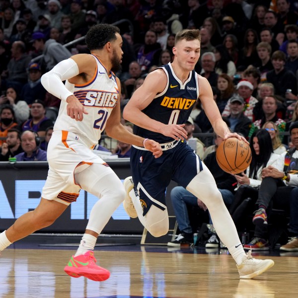 Denver Nuggets guard Christian Braun drives on Phoenix Suns guard Tyus Jones during the first half of an NBA basketball game, Wednesday, Dec. 25, 2024, in Phoenix. (AP Photo/Rick Scuteri)