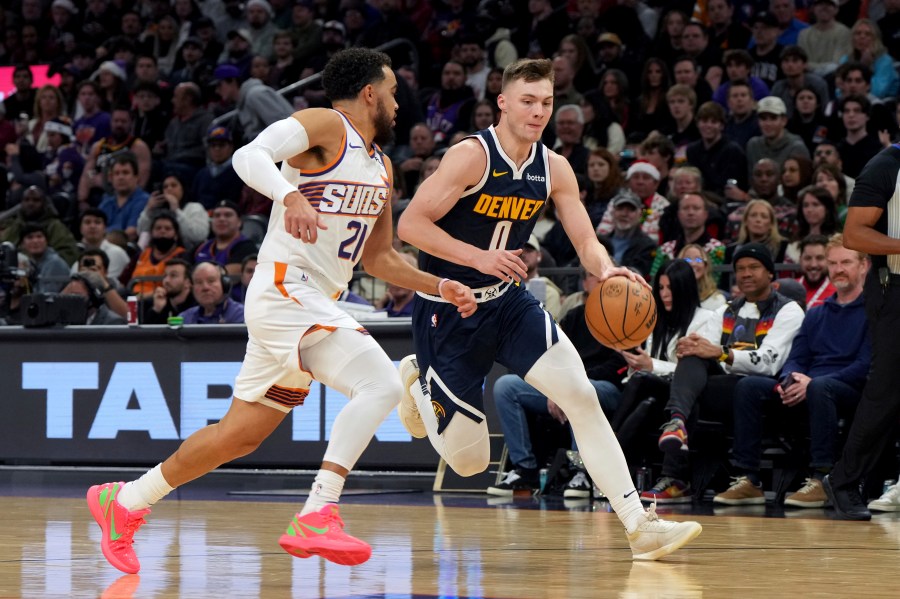 Denver Nuggets guard Christian Braun drives on Phoenix Suns guard Tyus Jones during the first half of an NBA basketball game, Wednesday, Dec. 25, 2024, in Phoenix. (AP Photo/Rick Scuteri)