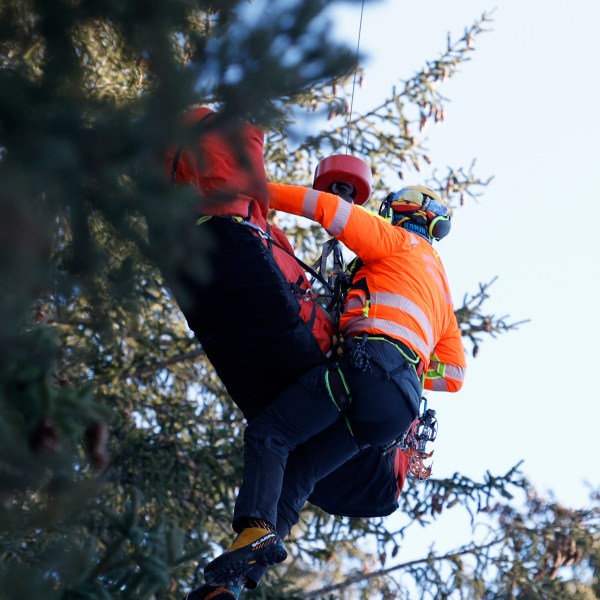 Medical staff are lifting France's Cyprien Sarrazin to an helicopter after crashing into protections net during an alpine ski, men's World Cup downhill training, in Bormio, Italy, Friday, Dec. 27, 2024. (AP Photo/Alessandro Trovati)