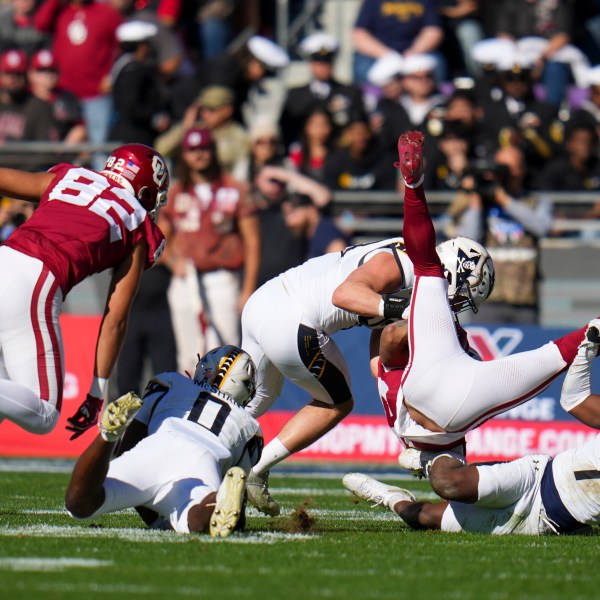 Oklahoma running back Gavin Sawchuk, second from right, is upended by Navy linebacker Mbiti Williams Jr. (7) and linebacker Kyle Jacob, center, during the first half of the Armed Forces Bowl NCAA college football game, Friday, Dec. 27, 2024, in Fort Worth, Texas. (AP Photo/Julio Cortez)