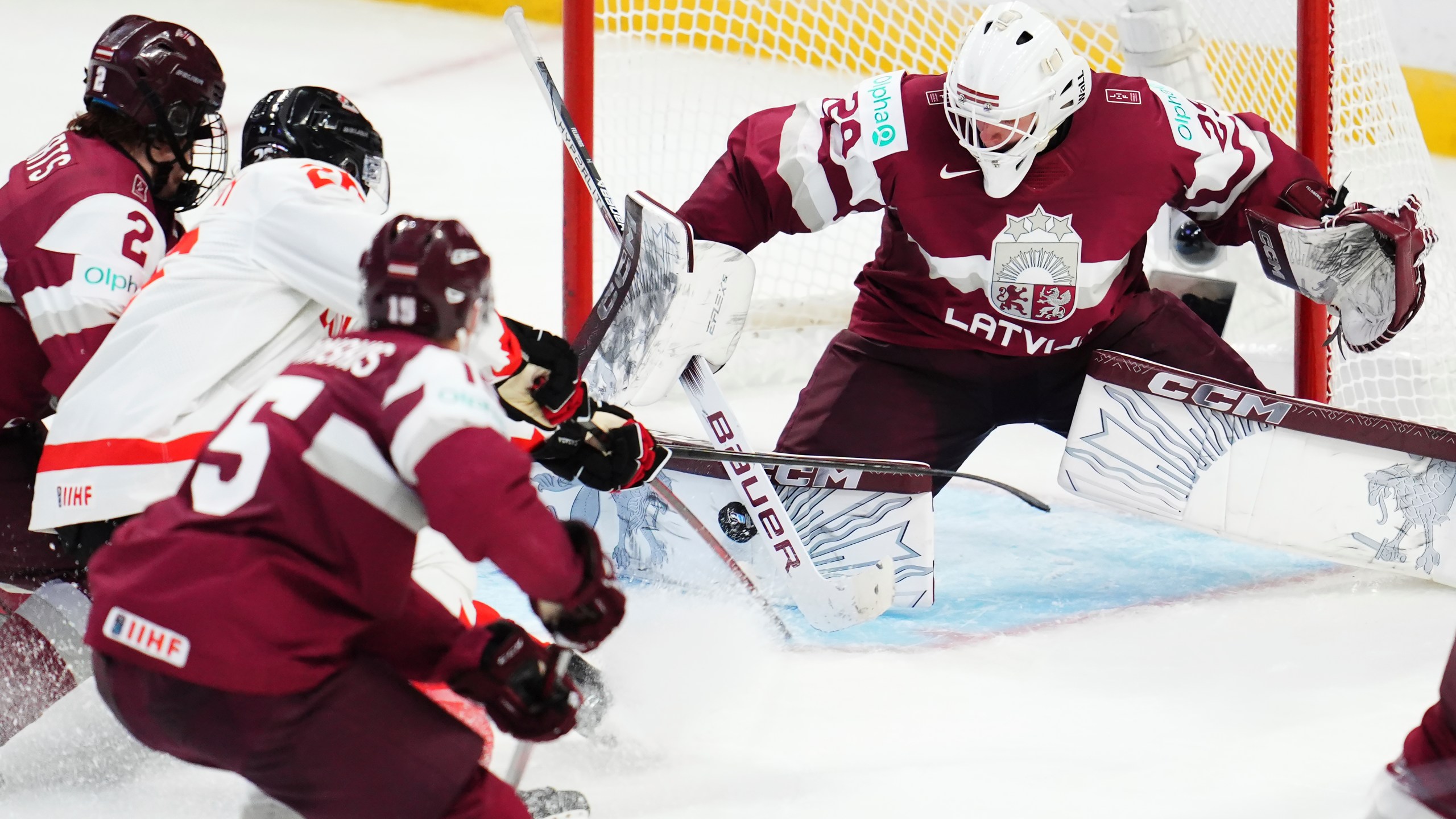 Latvia goaltender Linards Feldbergs (29) makes a save on Canada's Cole Beaudoin, second left, as Latvia's Krisjanis Sarts (2) defends during the third period of a IIHF World Junior Hockey Championship preliminary round game in Ottawa, Ontario on Friday, Dec. 27, 2024. (Sean Kilpatrick/The Canadian Press via AP)