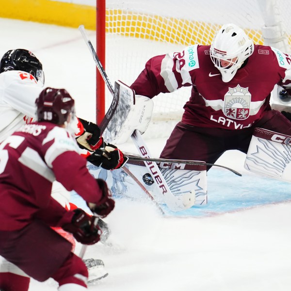 Latvia goaltender Linards Feldbergs (29) makes a save on Canada's Cole Beaudoin, second left, as Latvia's Krisjanis Sarts (2) defends during the third period of a IIHF World Junior Hockey Championship preliminary round game in Ottawa, Ontario on Friday, Dec. 27, 2024. (Sean Kilpatrick/The Canadian Press via AP)