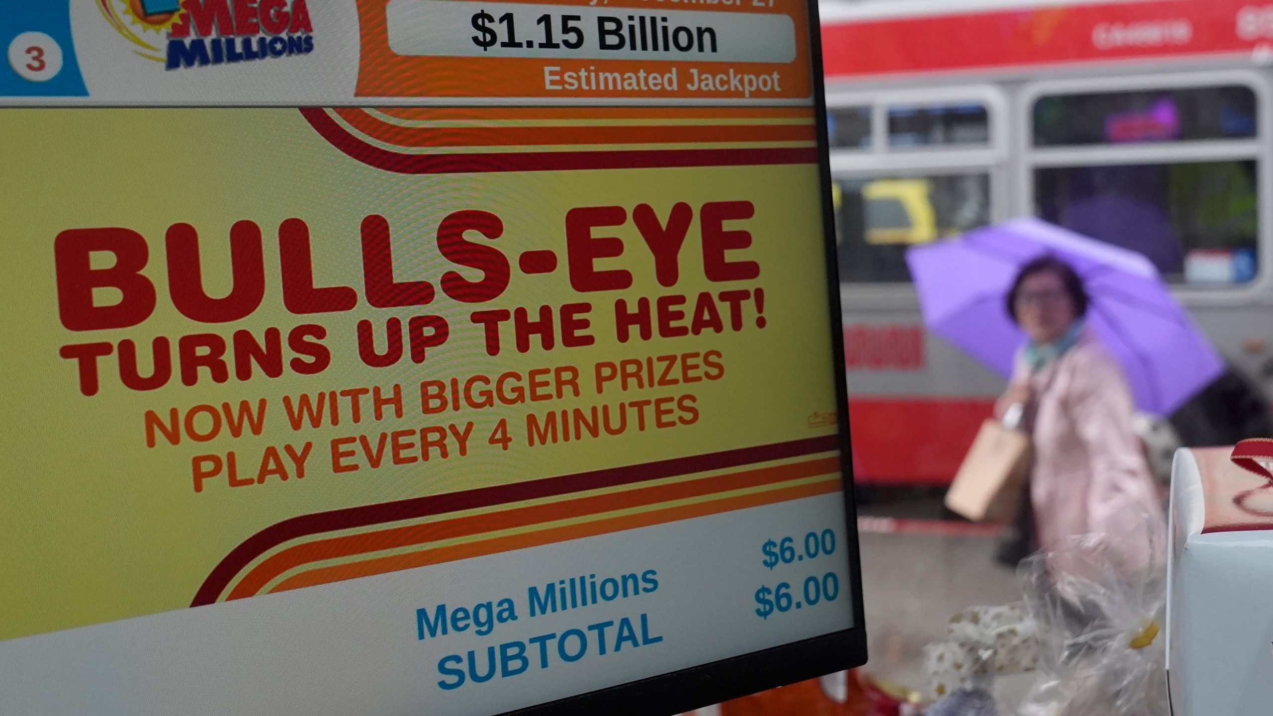 A pedestrian walks behind a sign advertising the estimated $1.15 billion Mega Millions jackpot at Rossi's Deli in San Francisco, Thursday, Dec. 26, 2024. (AP Photo/Jeff Chiu)