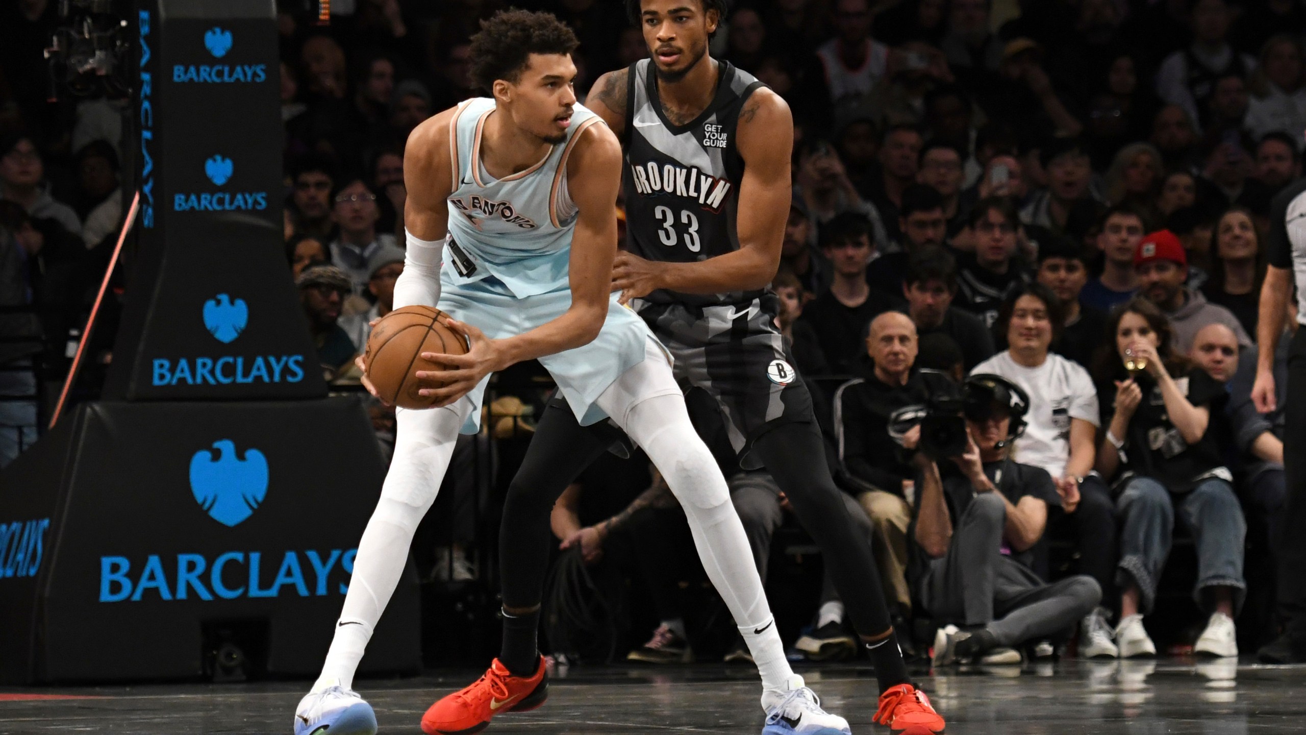 San Antonio Spurs' Victor Wembanyama, left, defends the ball from Brooklyn Nets' Nic Claxton, right, during the first half of an NBA basketball game Friday, Dec. 27, 2024, in New York. (AP Photo/Pamela Smith)