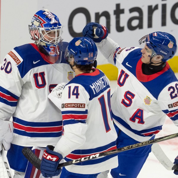 United States defenseman Aram Minnetian (14) and defenseman Zeev Buium (28) congratulate goaltender Hampton Slukynsky after a IIHF World Junior Hockey Championship tournament game against Latvia, Saturday, Dec.28, 2024 in Ottawa, Ontario. (Adrian Wyld/The Canadian Press via AP)