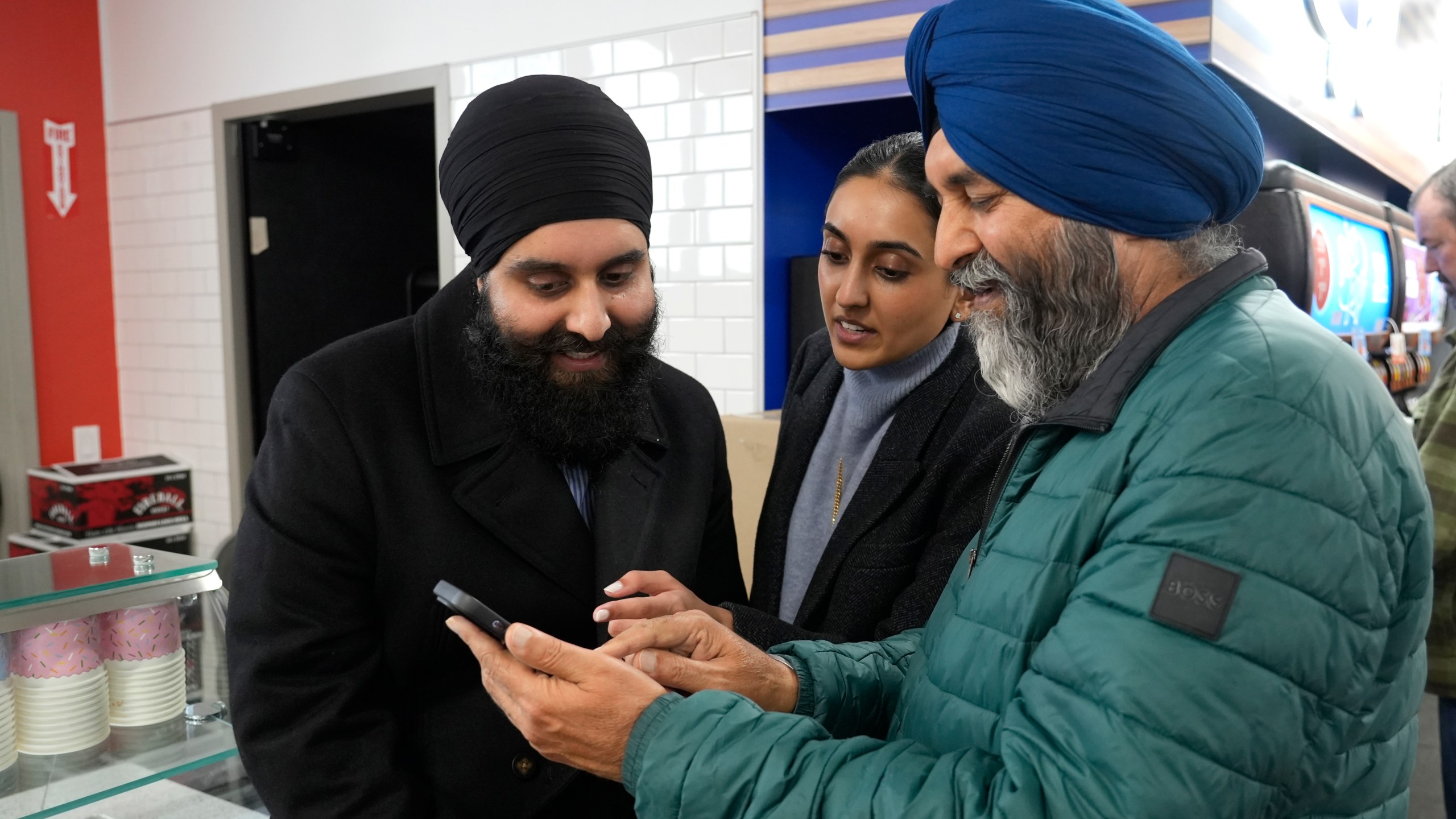 Ishar Gill, left, his sister Verdeen Gill, center and father Jaspal Singh. right, look over congratulatory texts for selling winning the Mega-Million lotto ticket worth an estimated $1.22 billion at the family's store in Cottonwood, Calif., Saturday, Dec. 28, 2024. After three months without anyone winning the top prize in the lottery, the ticket with the winning numbers was drawn Friday night.(AP Photo/Rich Pedroncelli).