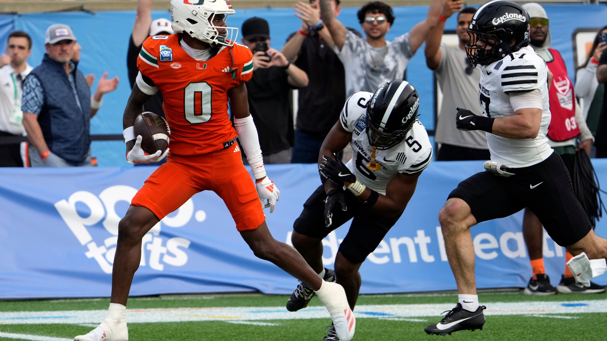 Miami wide receiver Joshisa Trader (0) scores a touchdown on a pass play as he gets past Iowa State defensive back Myles Purchase (5) and defensive back Beau Freyler, right, during the first half of the Pop Tarts Bowl NCAA college football game, Saturday, Dec. 28, 2024, in Orlando, Fla. (AP Photo/John Raoux)