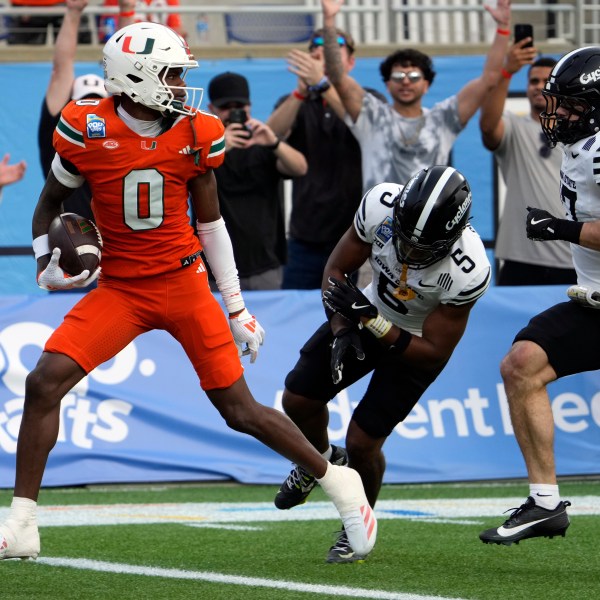 Miami wide receiver Joshisa Trader (0) scores a touchdown on a pass play as he gets past Iowa State defensive back Myles Purchase (5) and defensive back Beau Freyler, right, during the first half of the Pop Tarts Bowl NCAA college football game, Saturday, Dec. 28, 2024, in Orlando, Fla. (AP Photo/John Raoux)