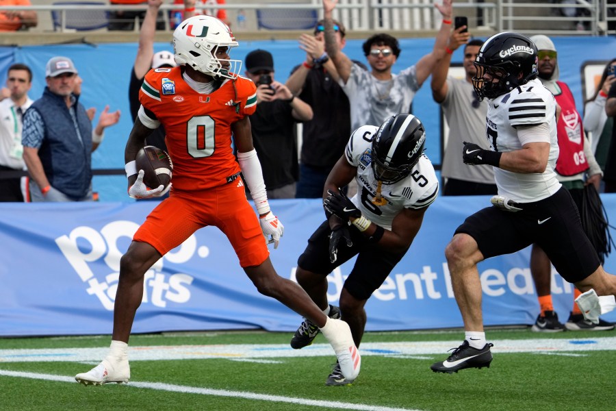 Miami wide receiver Joshisa Trader (0) scores a touchdown on a pass play as he gets past Iowa State defensive back Myles Purchase (5) and defensive back Beau Freyler, right, during the first half of the Pop Tarts Bowl NCAA college football game, Saturday, Dec. 28, 2024, in Orlando, Fla. (AP Photo/John Raoux)