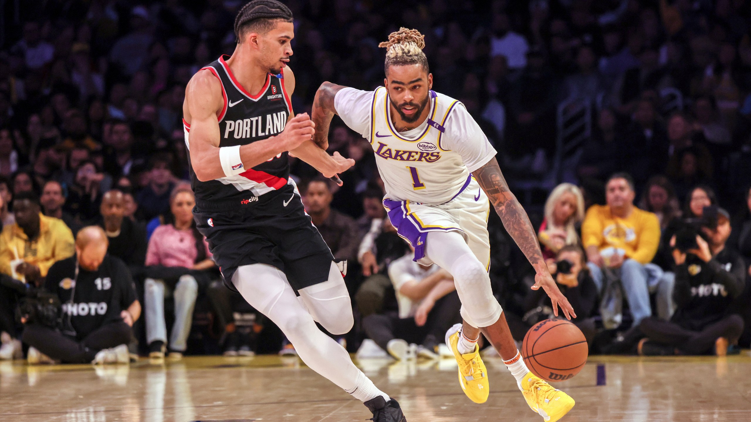 Los Angeles Lakers guard D'Angelo Russell, right, dribbles past Portland Trail Blazers forward Toumani Camara, left, during the first half of an NBA basketball game, Sunday, Dec. 8, 2024, in Los Angeles. (AP Photo/Etienne Laurent)