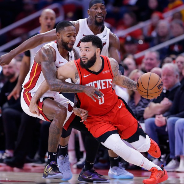 Houston Rockets guard Fred VanVleet (5) drives around Miami Heat forward Haywood Highsmith, left, as center Bam Adebayo, back, looks on during the first half of an NBA basketball game Sunday, Dec. 29, 2024, in Houston. (AP Photo/Michael Wyke)