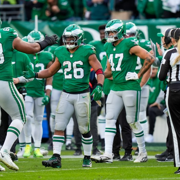 Philadelphia Eagles running back Saquon Barkley (26) is congratulated by offensive tackle Jordan Mailata and teammates after running for a long gain to put him at over 2,000 yards for the season during the second half of an NFL football game against the Dallas Cowboys, Sunday, Dec. 29, 2024, in Philadelphia. (AP Photo/Chris Szagola)