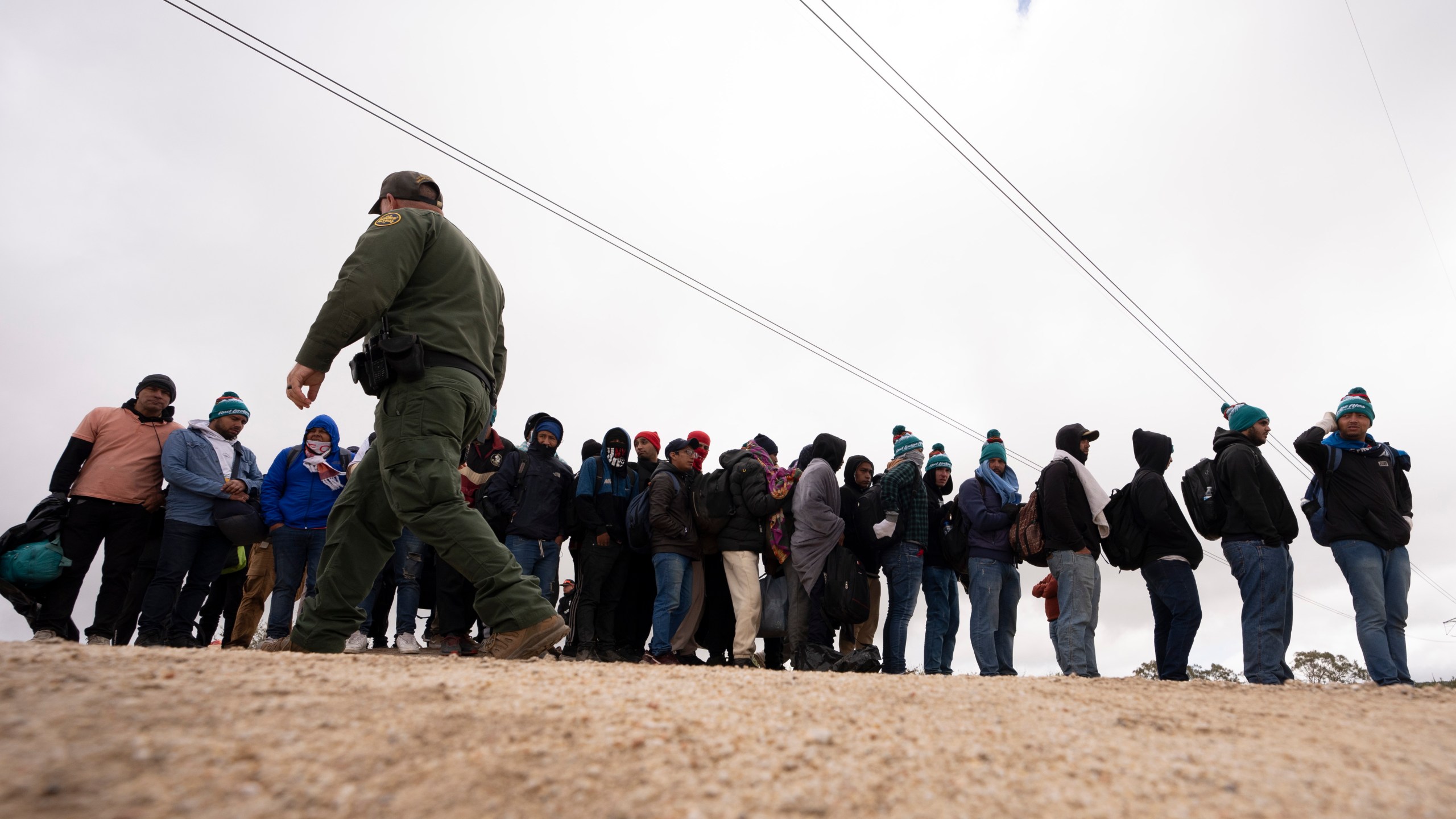 FILE - Men seeking asylum, including Peruvians, line up as they wait to be processed after crossing the border with Mexico nearby, on April 25, 2024, in Boulevard, Calif. (AP Photo/Gregory Bull, File)