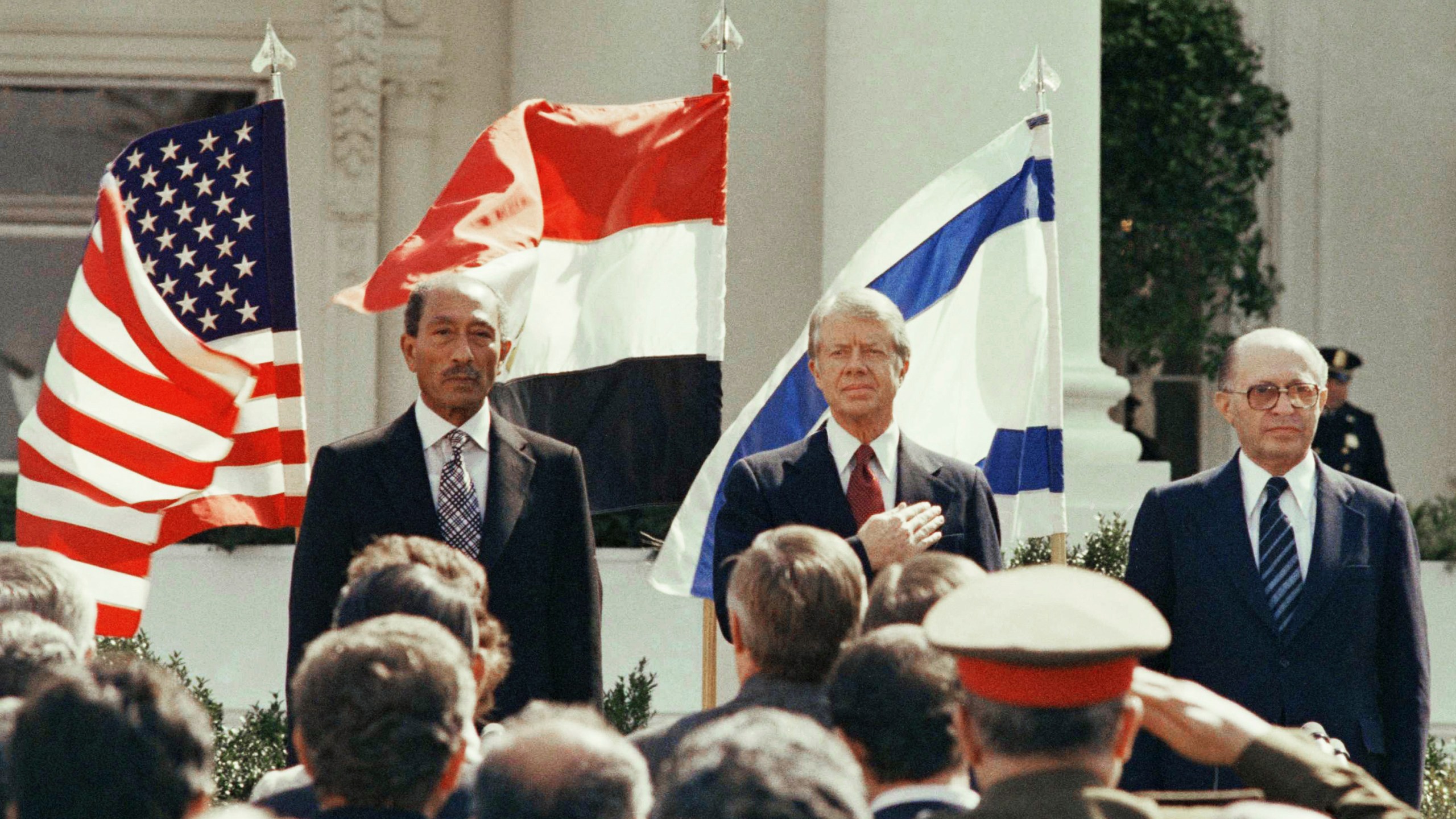 FILE - President Jimmy Carter stands in front of the billowing flags of Egypt, on the left, and Israel as the national anthems of the three countries are played before the signing of the peace treaty at the White House in Washington, March 26, 1979. (AP Photo, File)