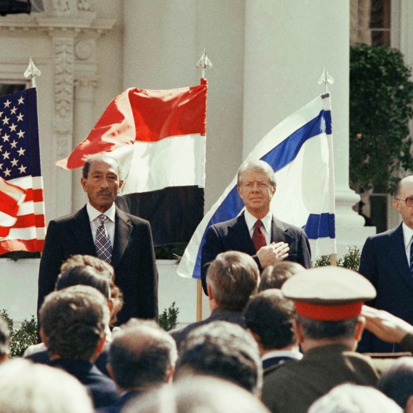 FILE - President Jimmy Carter stands in front of the billowing flags of Egypt, on the left, and Israel as the national anthems of the three countries are played before the signing of the peace treaty at the White House in Washington, March 26, 1979. (AP Photo, File)