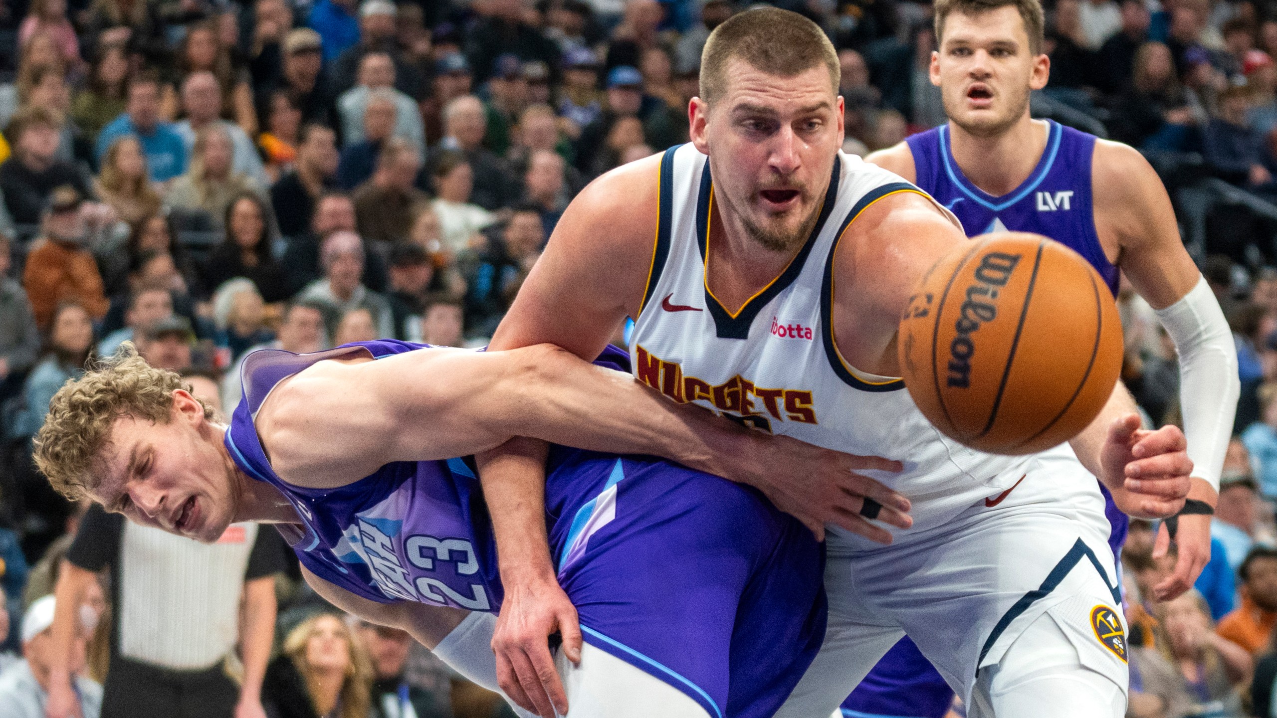 Denver Nuggets center Nikola Jokic, front right, becomes entangled with Utah Jazz forward Lauri Markkanen (23) as Jazz center Walker Kessler, back right, looks on during the first half of an NBA basketball game Monday, Dec. 30, 2024, in Salt Lake City. (AP Photo/Rick Egan)