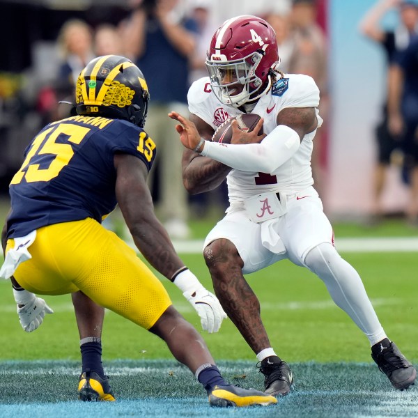 Alabama quarterback Jalen Milroe (4) cuts in front of Michigan linebacker Ernest Hausmann during the first half of the ReliaQuest Bowl NCAA college football game Tuesday, Dec. 31, 2024, in Tampa, Fla. (AP Photo/Chris O'Meara)