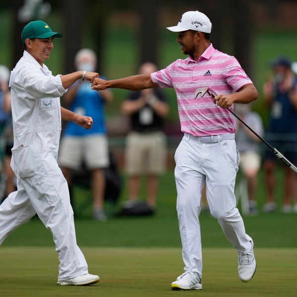 FILE - Xander Schauffele is congratulated by his caddie Austin Kaiser after an eagle on the 15th hole during the third round of the Masters golf tournament on Saturday, April 10, 2021, in Augusta, Ga. (AP Photo/Matt Slocum, File)