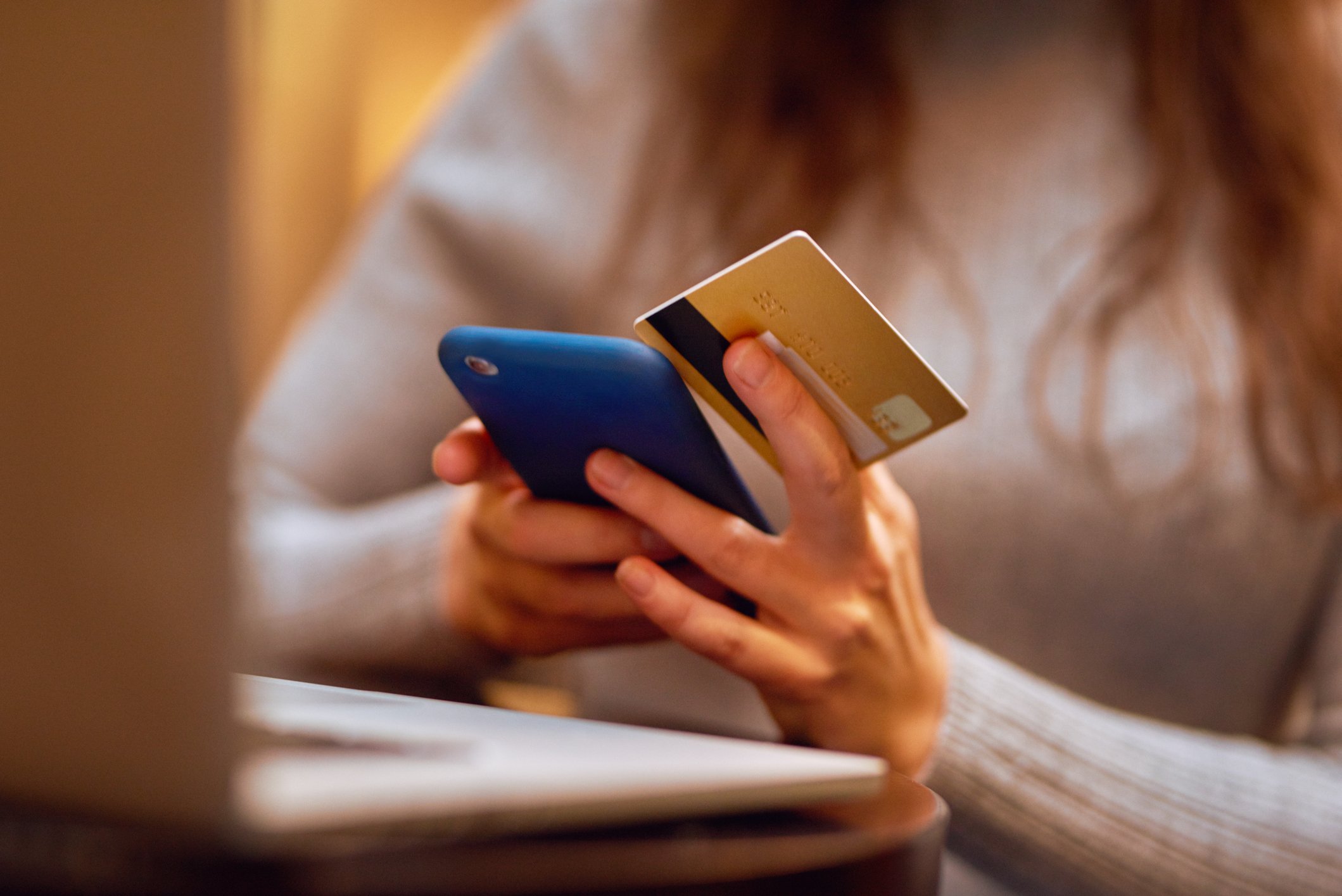 Closeup of an unrecognizable woman doing online shopping with her credit card and cellphone