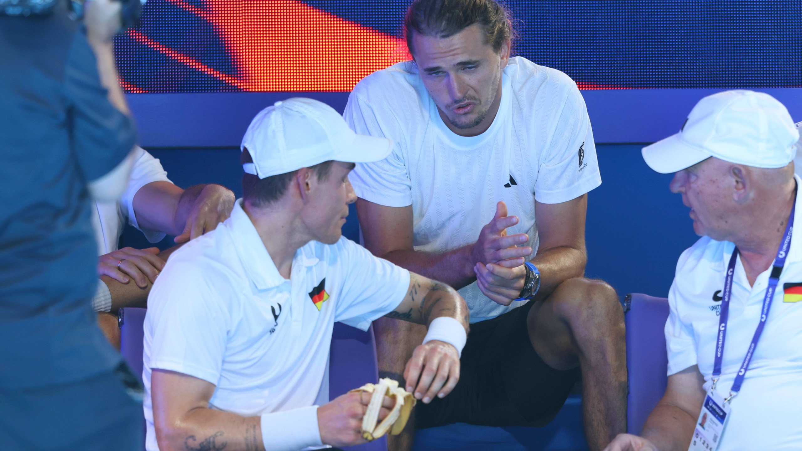 Alexander Zverev of Germany, center, talks to his replacement Daniel Masur, left, during a break in Germany's quarter final match against Alexander Shevchenko, after Zverev pulled out with a bicep injury from the United Cup tennis match in Perth, Australia, Wednesday, Jan. 1, 2025. (AP Photo/Trevor Collens)