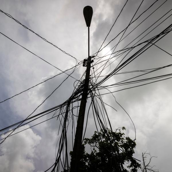 FILE - A utility pole with loose cables towers over a home in Loiza, Puerto Rico, Sept. 15, 2022. (AP Photo/Alejandro Granadillo, File)