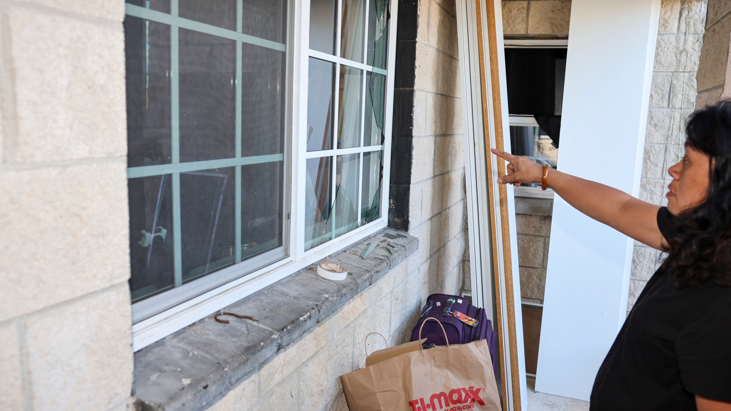 Evelyn Paguirigan points to broken windows at her home across the street from where a New Year's Eve fireworks explosion killed and injured people in Honolulu, on Wednesday, Jan. 1, 2025. (AP Photo/Marco Garcia)