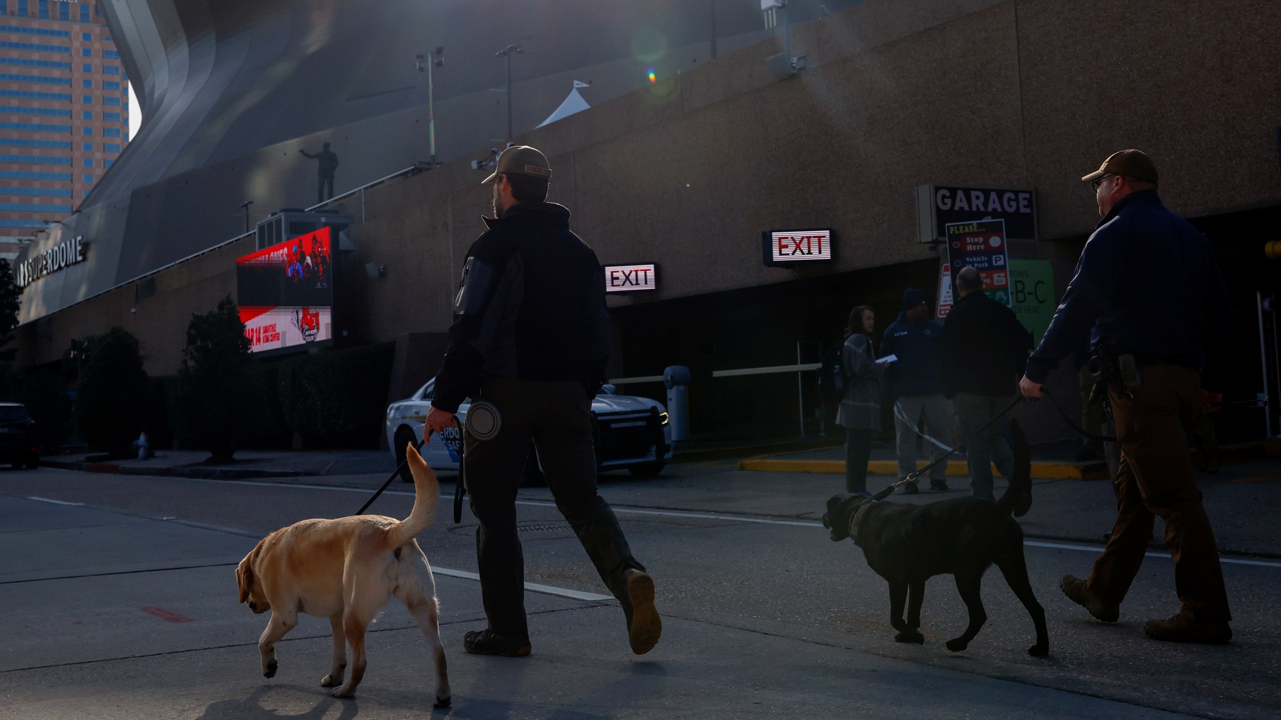 Security with bomb sniffing dogs patrol the area around the Superdome ahead of the Sugar Bowl NCAA College Football Playoff game, Thursday, Jan. 2, 2025, in New Orleans. (AP Photo/Butch Dill)