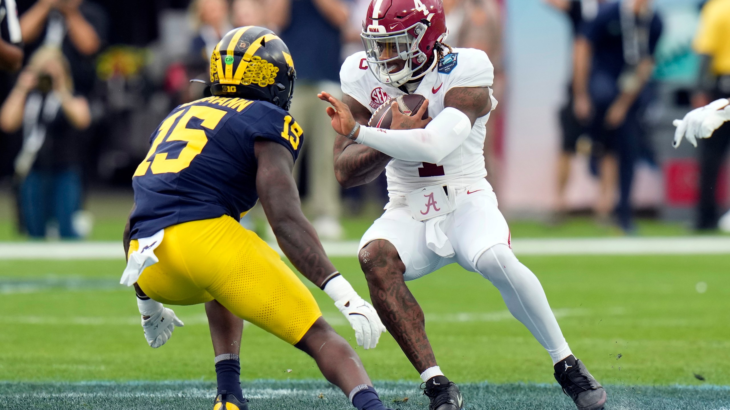 Alabama quarterback Jalen Milroe (4) cuts in front of Michigan linebacker Ernest Hausmann during the first half of the ReliaQuest Bowl NCAA college football game Tuesday, Dec. 31, 2024, in Tampa, Fla. (AP Photo/Chris O'Meara)