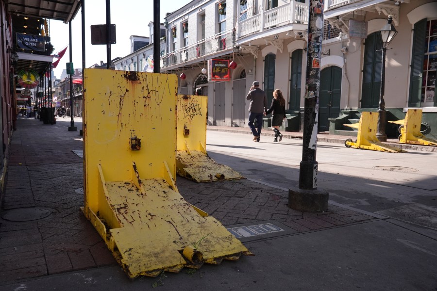 Tourist walk past temporary barriers on Bourbon Street, Thursday, Jan. 2, 2025 in New Orleans. (AP Photo/George Walker IV)