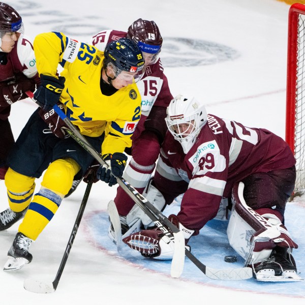 Team Sweden forward Otto Stenberg (25) tries to score on Team Latvia goaltender Linards Feldbergs (29) as Latvia forward Davis Livsics (7) and defenseman Darels Uljanskis (15) defend during the third period of an IIHF World Junior Hockey Championship quarterfinal match in Ottawa, Ontario Thursday, Jan. 2, 2025. (Spencer Colby/The Canadian Press via AP)