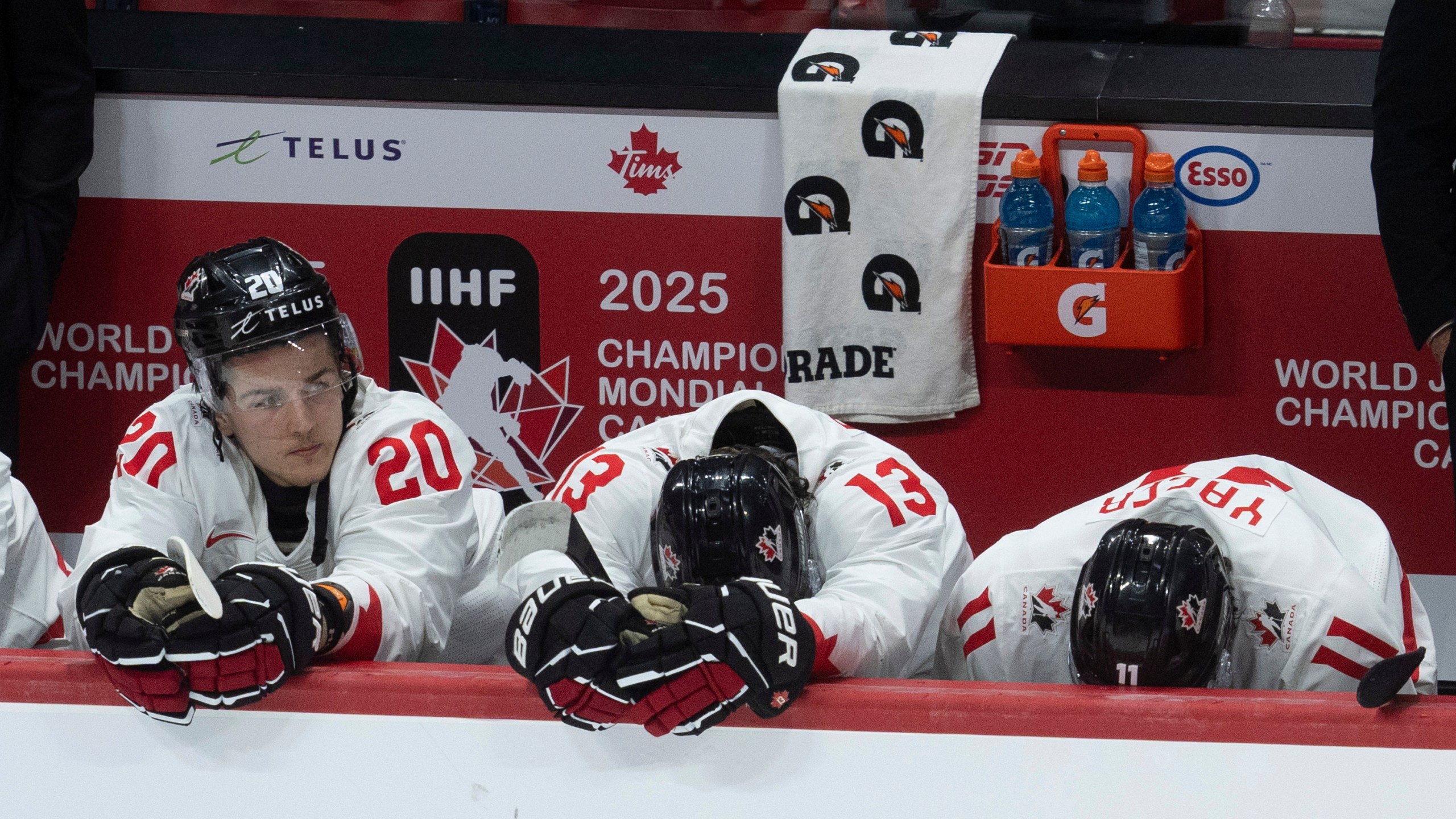 Canada forward Ethan Gauthier (20) sits on the bench alongside teammates Luca Pinelli (13) and Brayden Yager (11) during the third period of a quarterfinal match at the world junior hockey championship against Czech Republic in Ottawa, Ontario, Thursday, Jan. 2, 2025. (Adrian Wyld/The Canadian Press via AP)