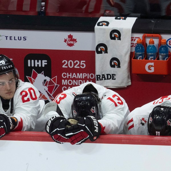 Canada forward Ethan Gauthier (20) sits on the bench alongside teammates Luca Pinelli (13) and Brayden Yager (11) during the third period of a quarterfinal match at the world junior hockey championship against Czech Republic in Ottawa, Ontario, Thursday, Jan. 2, 2025. (Adrian Wyld/The Canadian Press via AP)