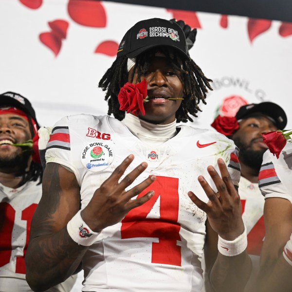 Ohio State wide receiver Jeremiah Smith (4) holds a rose in his mouth as he celebrates after the quarterfinals of the Rose Bowl College Football Playoff against Oregon, Wednesday, Jan. 1, 2025, in Pasadena, Calif. (AP Photo/Kyusung Gong)