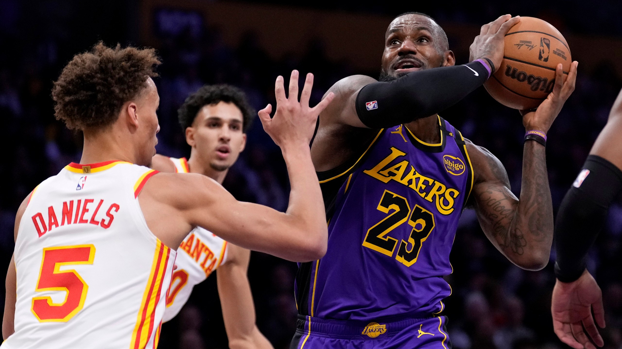 Los Angeles Lakers forward LeBron James, right, shoots as Atlanta Hawks guard Dyson Daniels defends during the first half of an NBA basketball game, Friday, Jan. 3, 2025, in Los Angeles. (AP Photo/Mark J. Terrill)