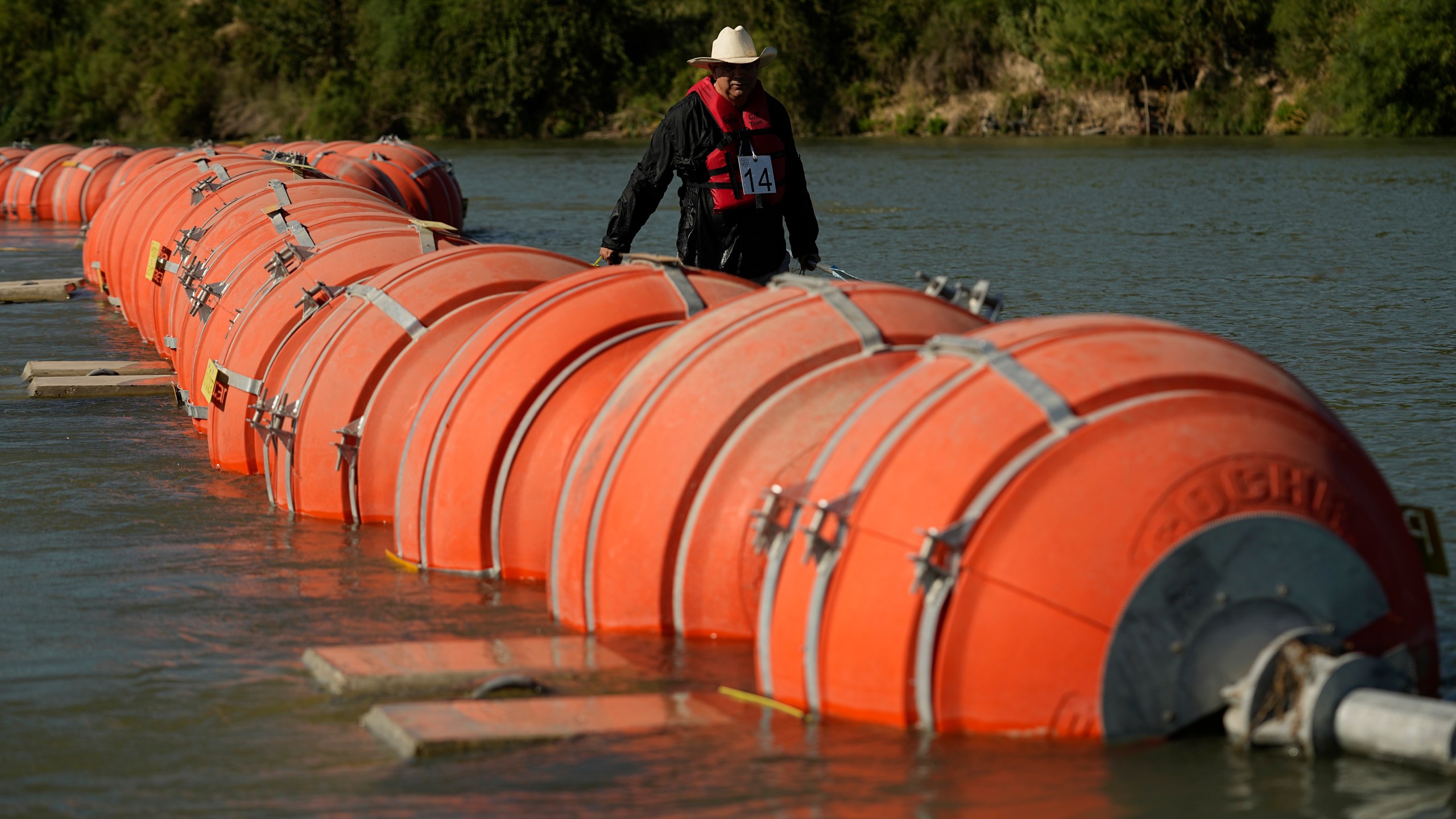 FILE - A kayaker walks past large buoys being used as a floating border barrier on the Rio Grande, Aug. 1, 2023, in Eagle Pass, Texas. (AP Photo/Eric Gay, File)