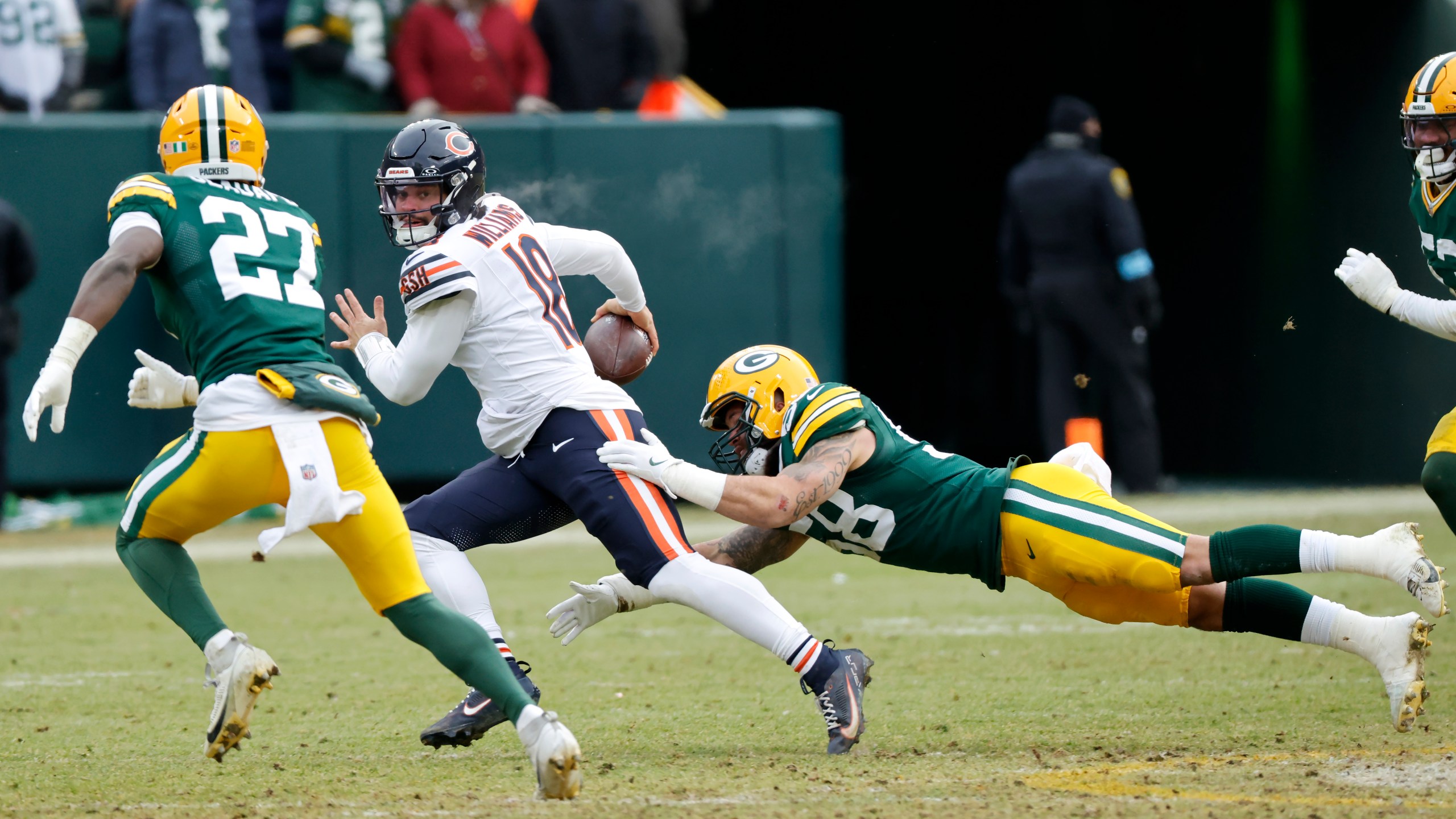 Chicago Bears quarterback Caleb Williams, middle, scrambles against Green Bay Packers linebacker Isaiah McDuffie, bottom, and safety Kitan Oladapo (27) during the second half of an NFL football game, Sunday, Jan. 5, 2025, in Green Bay, Wis. (AP Photo/Mike Roemer)