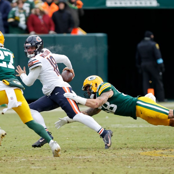 Chicago Bears quarterback Caleb Williams, middle, scrambles against Green Bay Packers linebacker Isaiah McDuffie, bottom, and safety Kitan Oladapo (27) during the second half of an NFL football game, Sunday, Jan. 5, 2025, in Green Bay, Wis. (AP Photo/Mike Roemer)