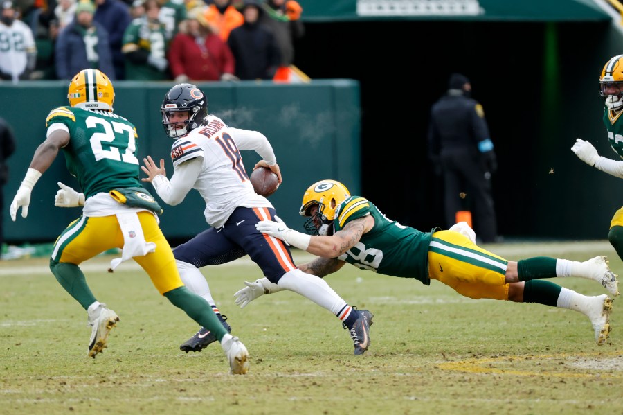 Chicago Bears quarterback Caleb Williams, middle, scrambles against Green Bay Packers linebacker Isaiah McDuffie, bottom, and safety Kitan Oladapo (27) during the second half of an NFL football game, Sunday, Jan. 5, 2025, in Green Bay, Wis. (AP Photo/Mike Roemer)