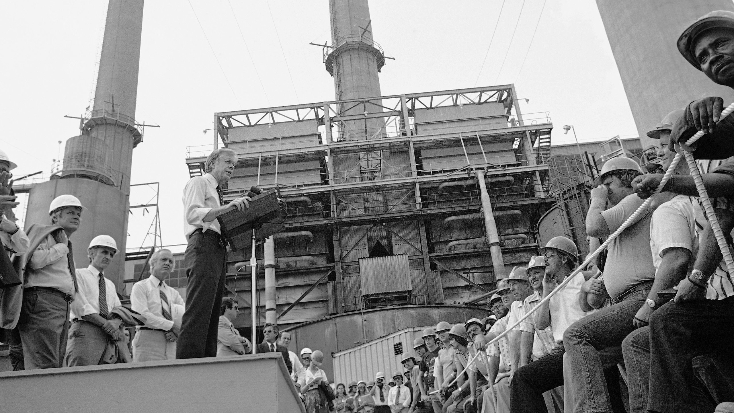 FILE - President Jimmy Carter talks to power plant workers against a backdrop of tall stacks at the Louisville Gas and Electric Company plant in Louisville, Ky., July 31, 1979. (AP Photo, File)