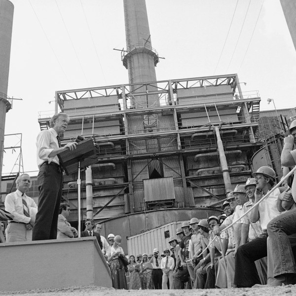 FILE - President Jimmy Carter talks to power plant workers against a backdrop of tall stacks at the Louisville Gas and Electric Company plant in Louisville, Ky., July 31, 1979. (AP Photo, File)