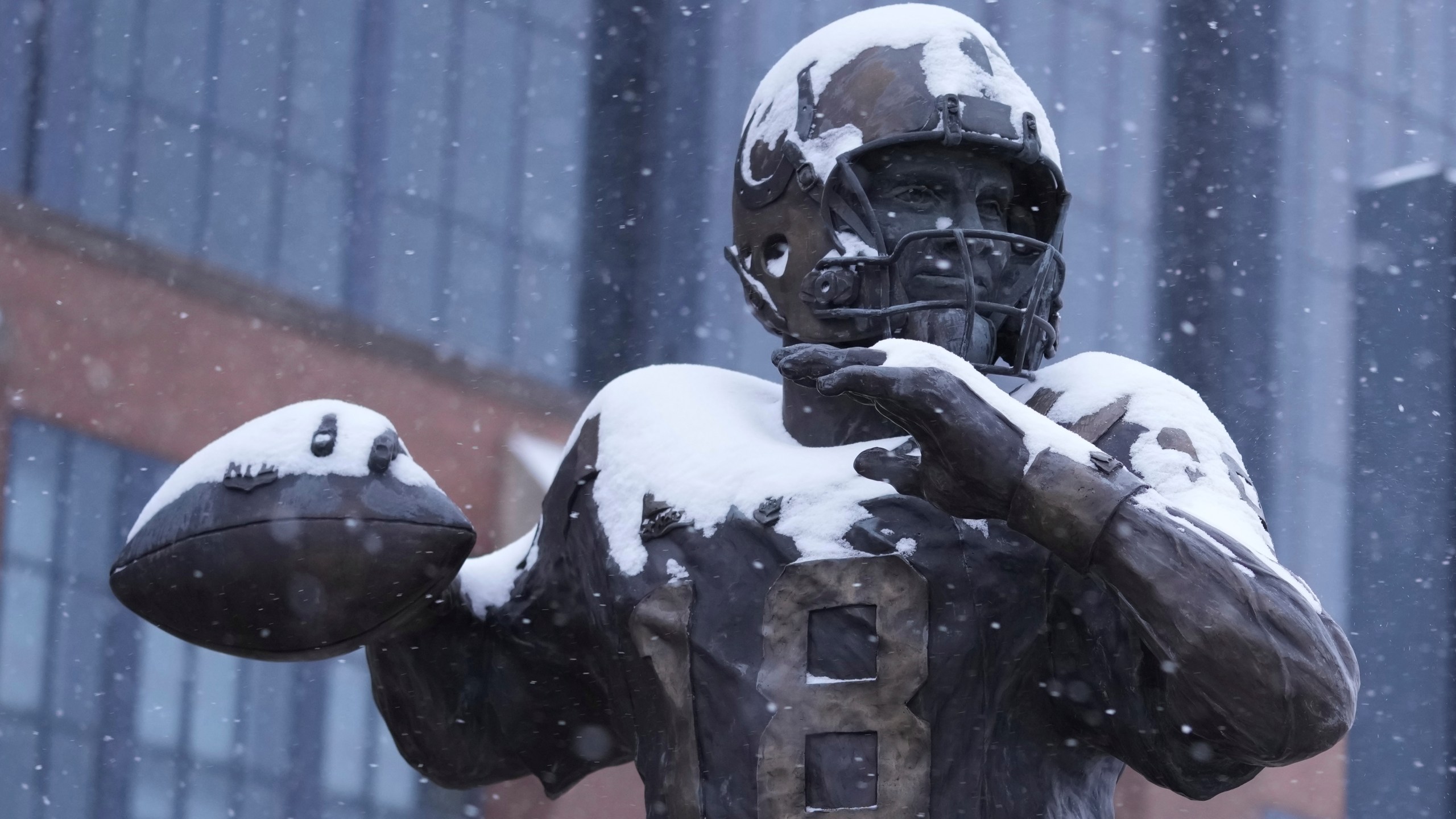 A statue of Peyton Manning by Ryan Feeney is dusted with snow outside Lucas Oil Stadium after an NFL football game between the Indianapolis Colts and the Jacksonville Jaguars, Sunday, Jan. 5, 2025, in Indianapolis. (AP Photo/Michael Conroy)