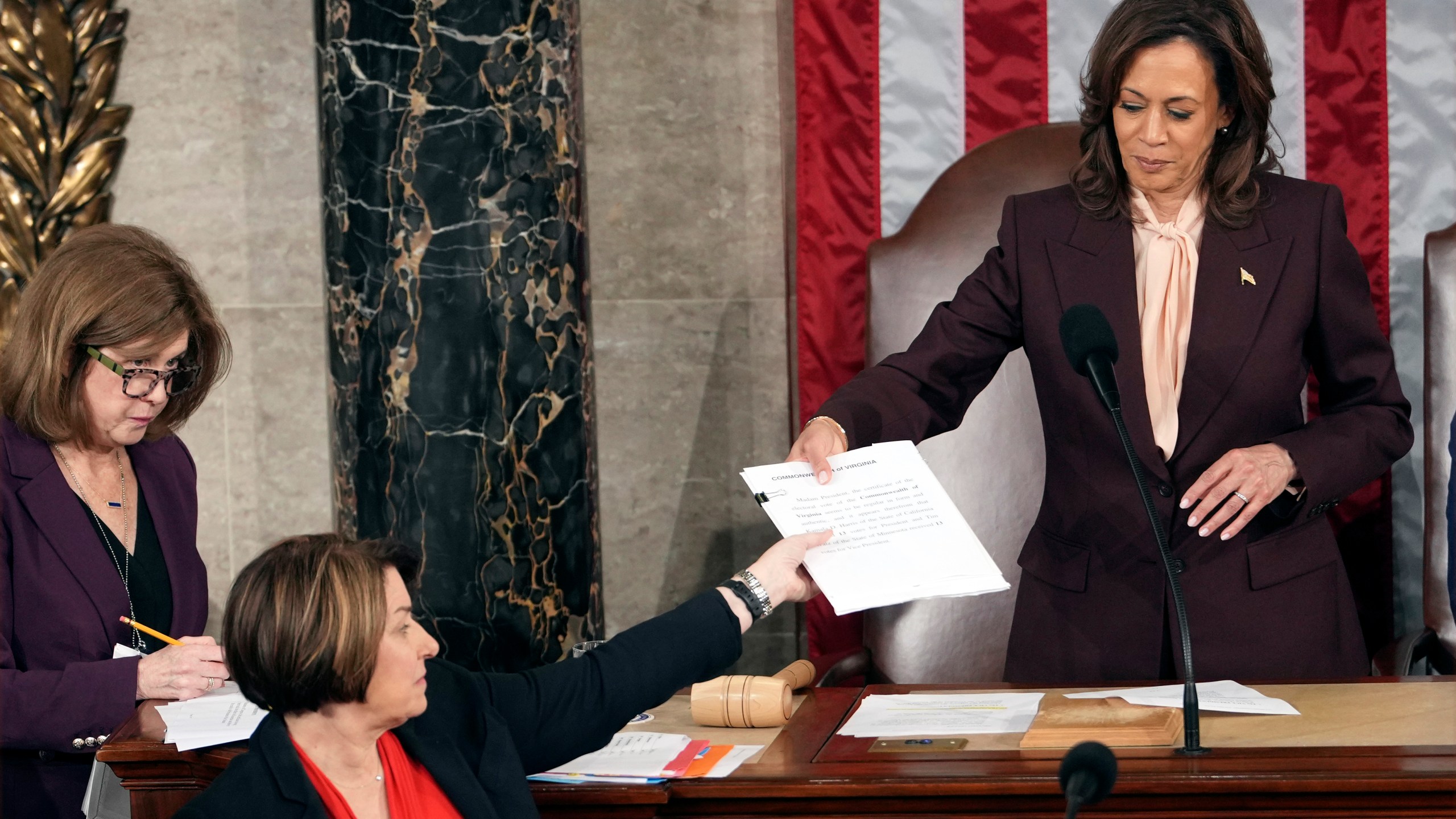 Vice President Kamala Harris hands the certification for Virginia to teller Sen. Amy Klobuchar, D-Minn., during joint session of Congress to confirm the Electoral College votes, affirming President-elect Donald Trump's victory in the presidential election, Monday, Jan. 6, 2025, at the U.S. Capitol in Washington. (AP Photo/Matt Rourke)