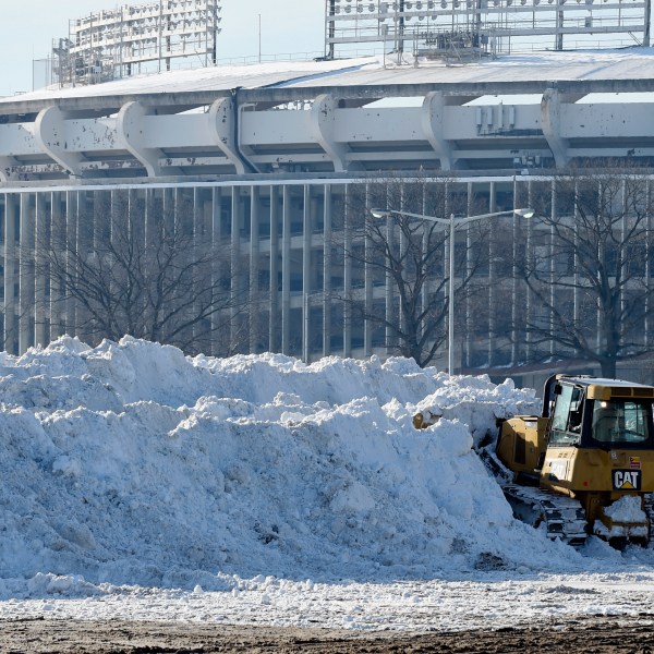 FILE - A vehicle pushes up pikes of snow after trucks dump their loads of snow in the parking lots of RFK Stadium in Washington, Monday, Jan. 25, 2016. (AP Photo/Susan Walsh, File)