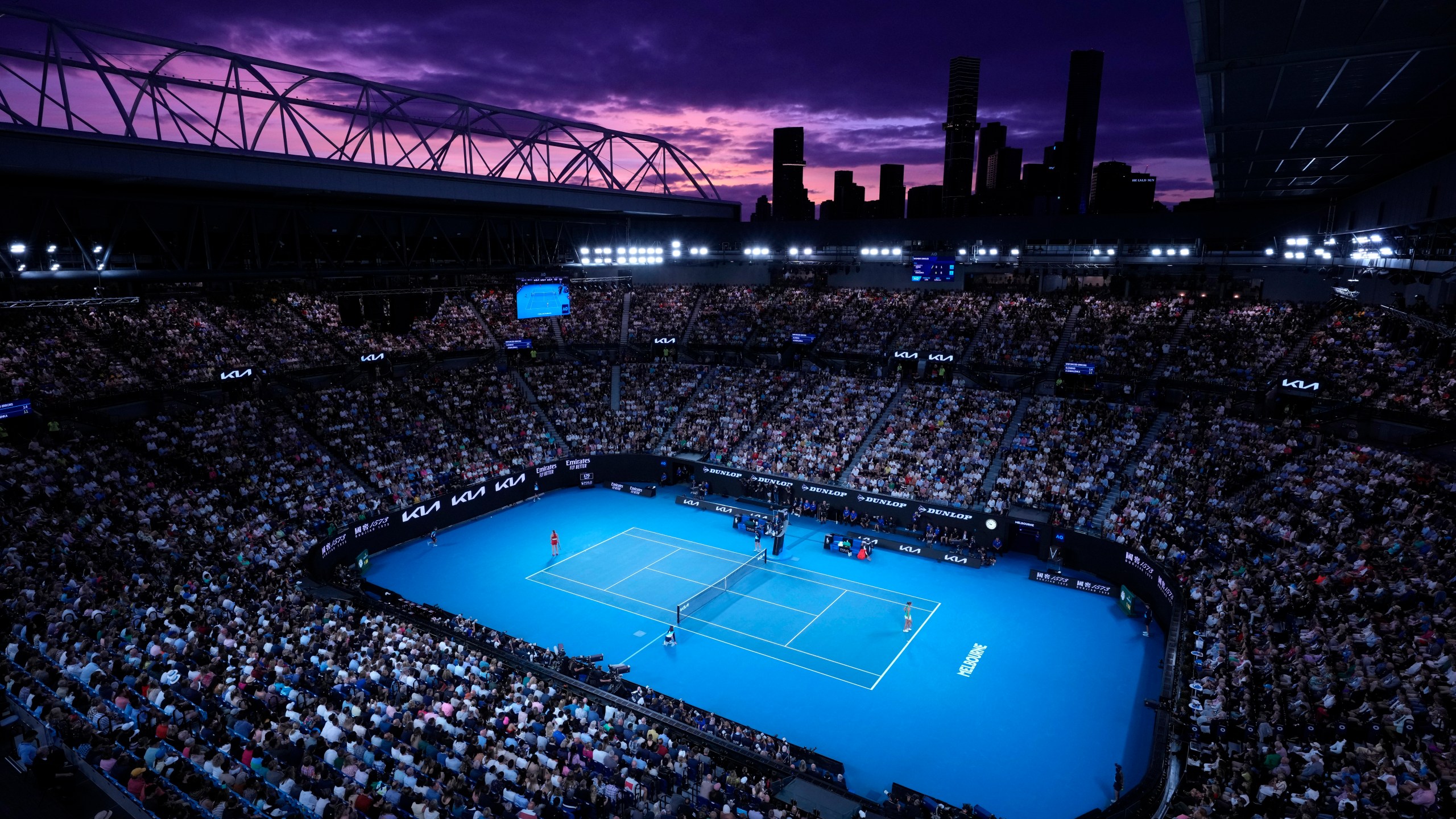 FILE - Aryna Sabalenka of Belarus, left, and Zheng Qinwen of China play as the sun sets during the women's singles final at the Australian Open tennis championships at Melbourne Park, Melbourne, Australia, Jan. 27, 2024. (AP Photo/Louise Delmotte, File)