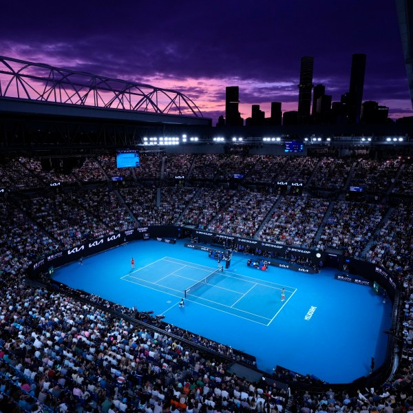 FILE - Aryna Sabalenka of Belarus, left, and Zheng Qinwen of China play as the sun sets during the women's singles final at the Australian Open tennis championships at Melbourne Park, Melbourne, Australia, Jan. 27, 2024. (AP Photo/Louise Delmotte, File)