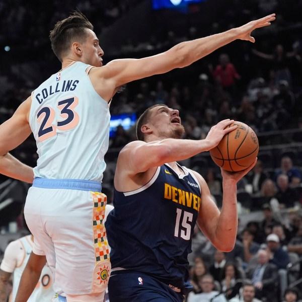 Denver Nuggets center Nikola Jokic (15) drives to the basket against San Antonio Spurs forward Zach Collins (23) during the first half of an NBA basketball game in San Antonio, Saturday, Jan. 4, 2025. (AP Photo/Eric Gay)