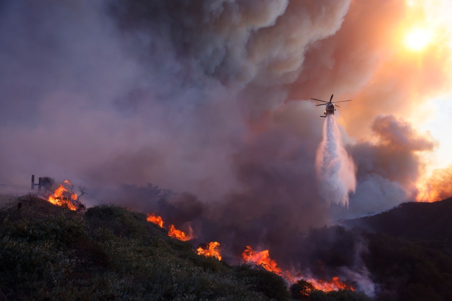 Water is dropped by helicopter on the advancing Palisades Fire in the Pacific Palisades neighborhood of Los Angeles, Tuesday, Jan. 7, 2025. (AP Photo/Etienne Laurent)